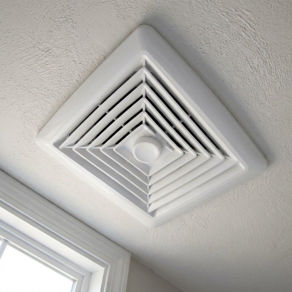 A clean white bathroom exhaust fan mounted on a ceiling